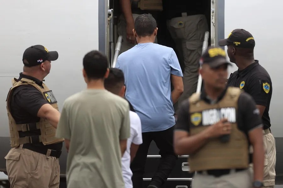 Fotografía de archivo de personas subiendo a un avión mientras son custodiadas por integrantes del Servicio Nacional de Migración de Panamá. EFE/ Bienvenido Velasco