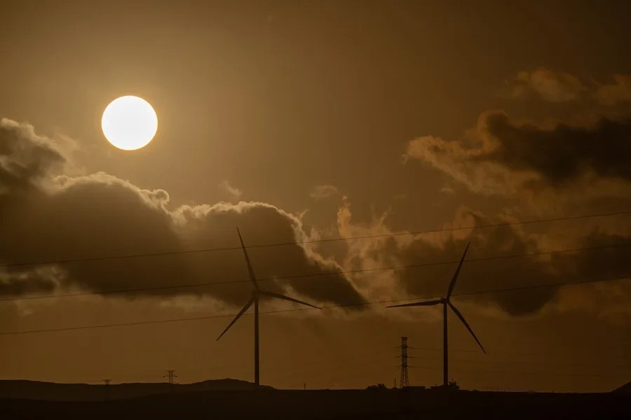 El sol se pone tras unos aerogeneradores durante el atardecer en Puerto del Rosario (Fuerteventura).