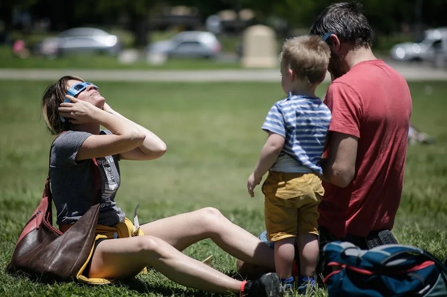 Una mujer observa el eclipse solar con lentes especiales