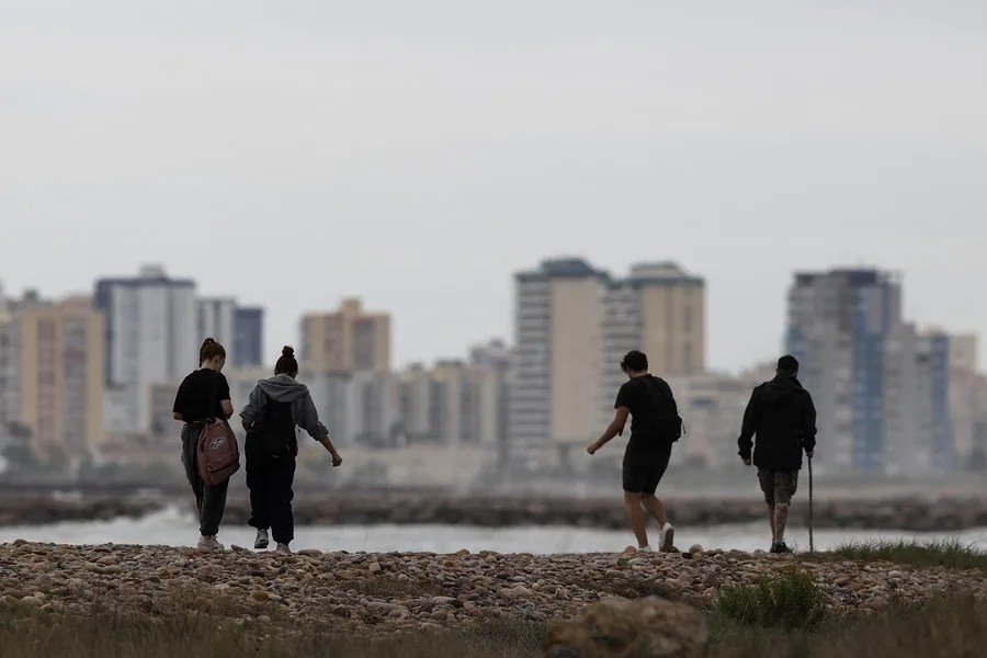 Unos jóvenes pasean por la playa de Pobla de Farnals, en Valencia