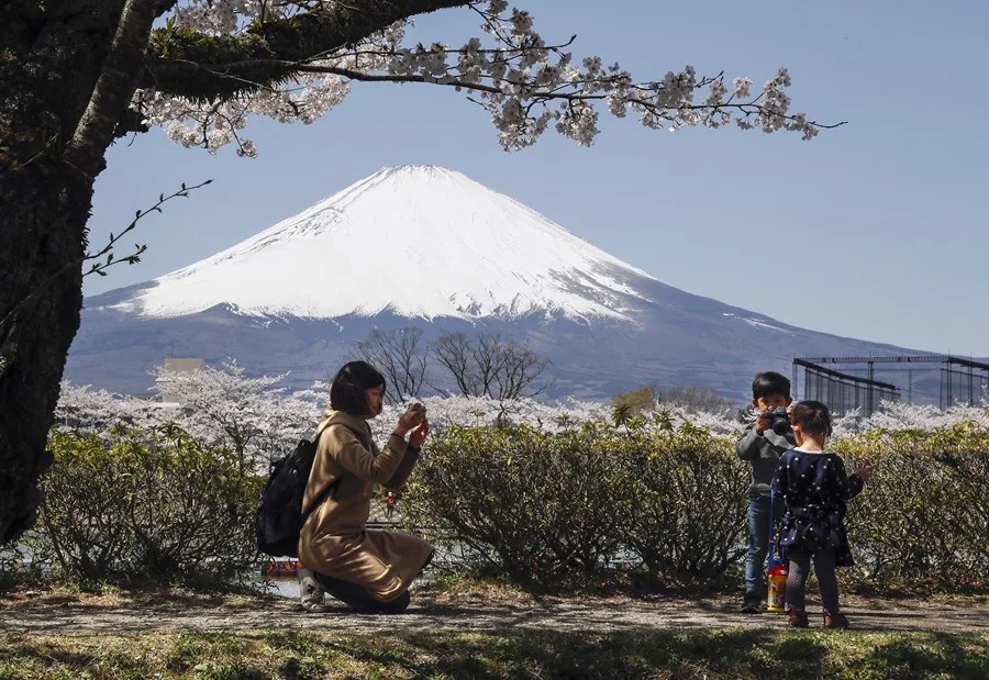 Una madre toma fotos de su hijo tomando fotos de su hija en un mirador del pico más alto de Japón, el Monte Fuji,