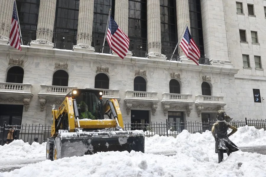 Los trabajadores limpian la nieve cerca de la escultura 'The Fearless Girl' frente a la Bolsa de Valores de Nueva York