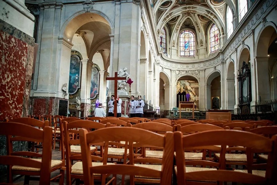 Sacerdote y oficiante rezan ante una cruz