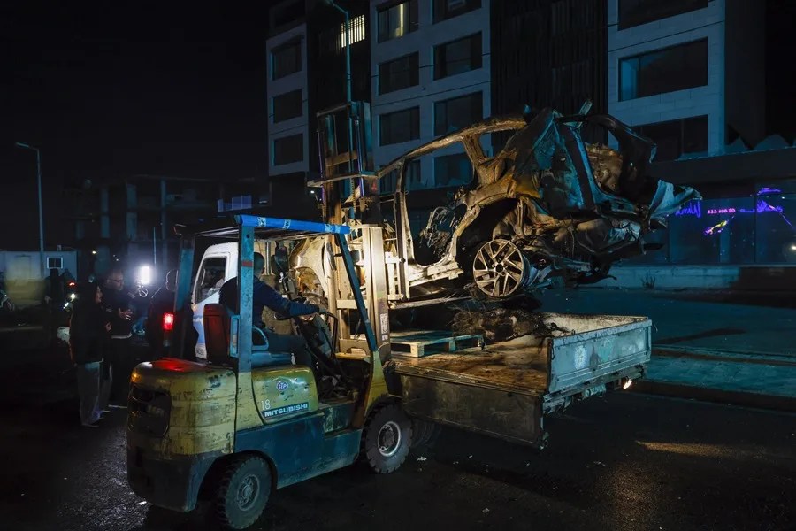 Trabajadores municipales, junto con simpatizantes de Hezbolá, retiran un vehículo incendiado de una calle junto a la autopista que conduce al Aeropuerto Internacional de Beirut,