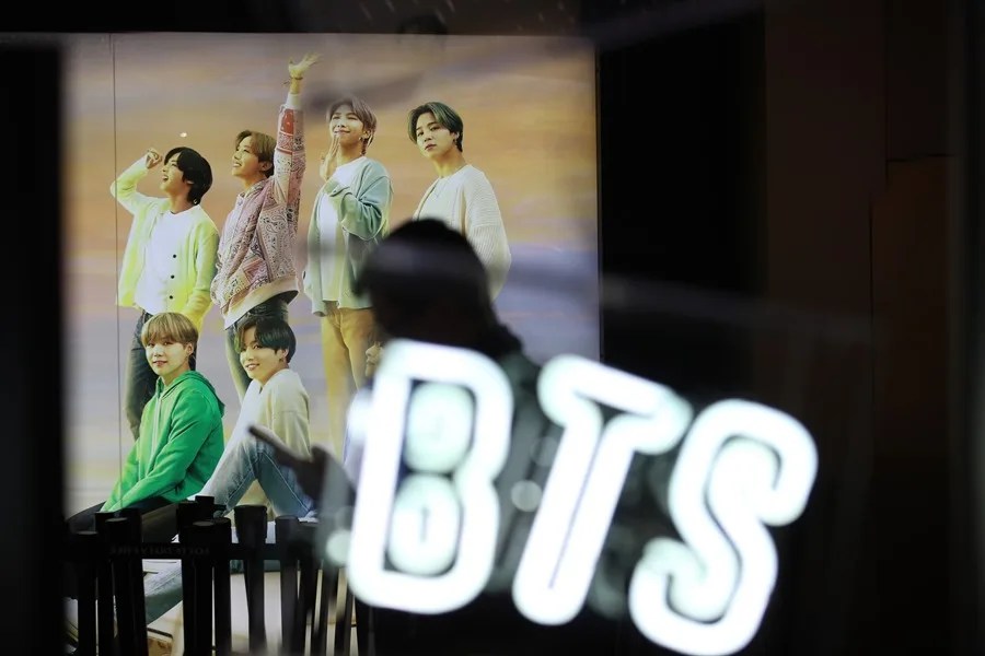 Una mujer pasa junto a una foto del grupo de K-pop BTS
