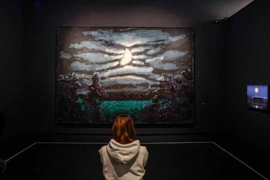 Un visitante se encuentra junto a las obras de arte del artista inglés David Hockney 