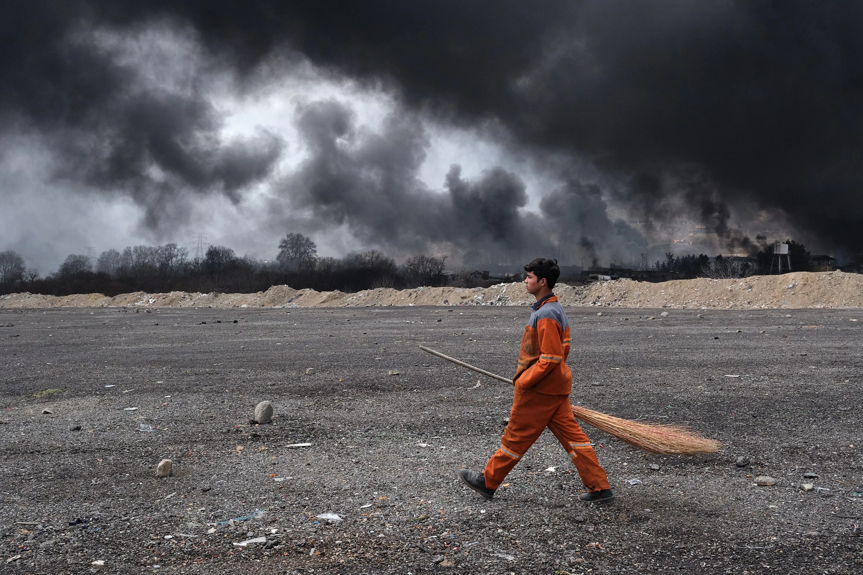 Un barrendero camina por delante del Depósito de Petróleo del Noroeste de Teherán que fue atacado anoche por