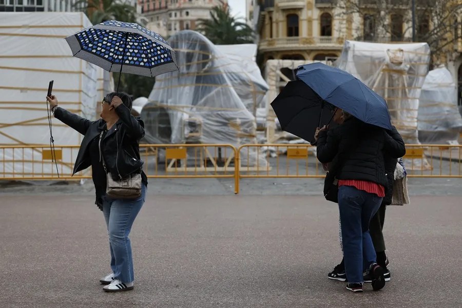 Turistas se fotografían bajo sus paraguas, este sábado en Valencia