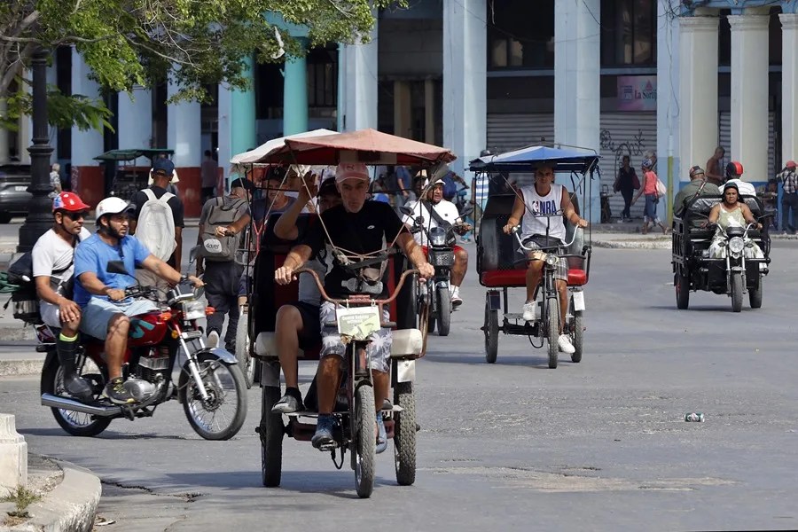 Personas viajan en bicitaxis en La Habana