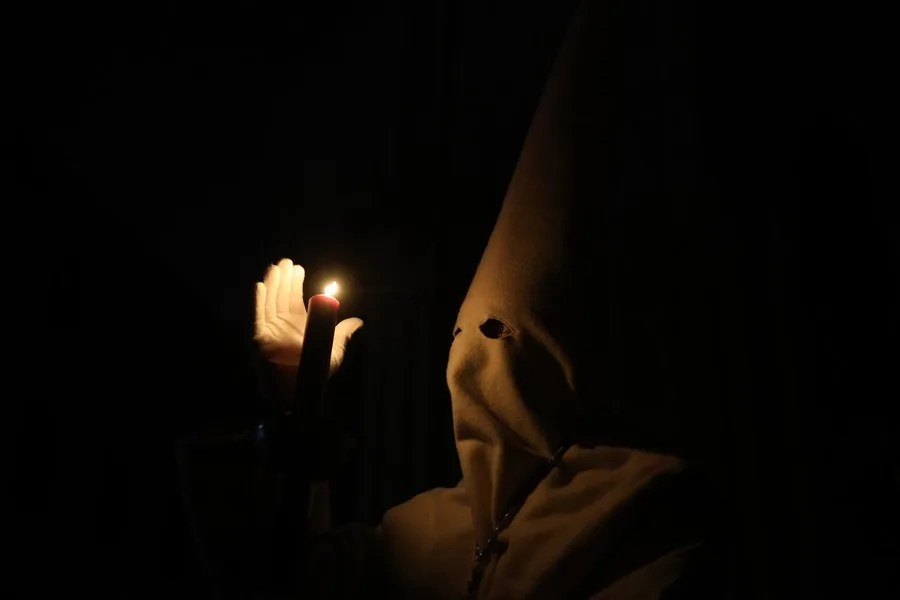 Un nazareno de la Penitente Hermandad de Jesús Yacente participa en la procesión del paso de Jesús Yacente