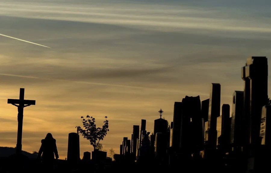 Una mujer camina junto a las tumbas en un cementerio en Austria