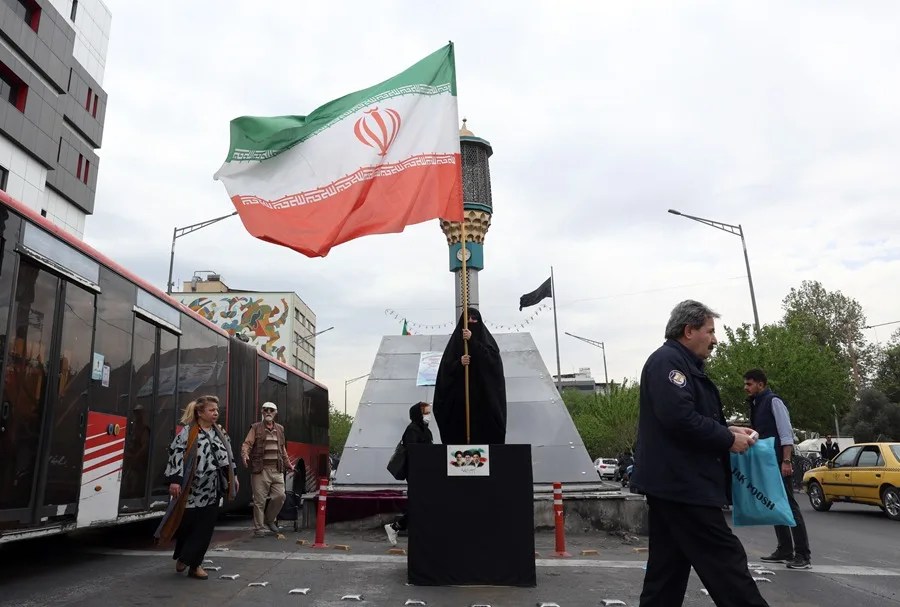Una mujer porta una bandera de Irán, hoy por las calles de Teherán.