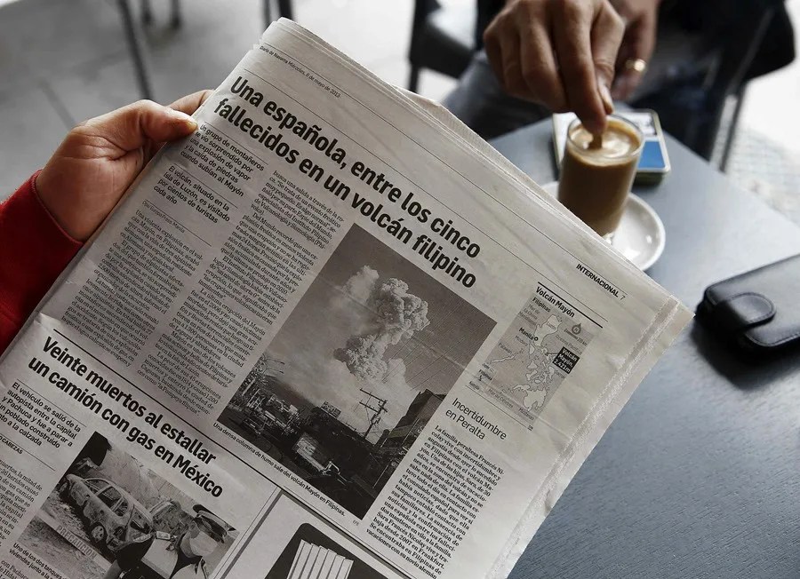 Una persona lee una noticia en un periódico.