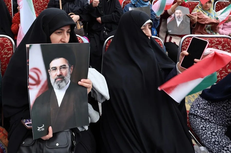 Una mujer iraní vestida con un chador negro sostiene un cartel del líder supremo iraní, el ayatolá Mojtaba Khamenei