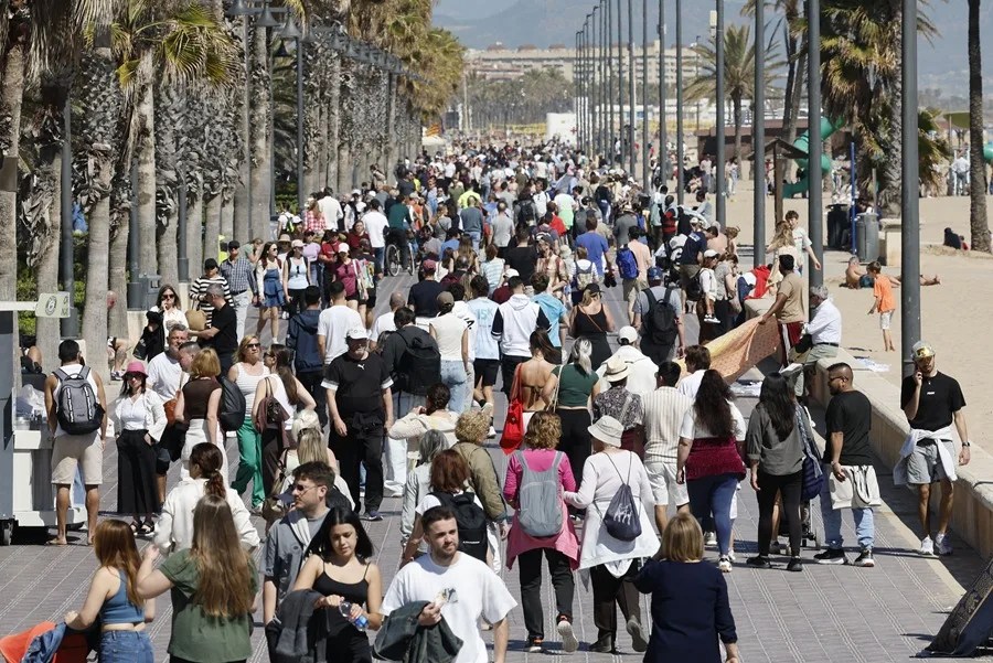 Residentes y turistas pasean junto a la Playa de Las Arenas