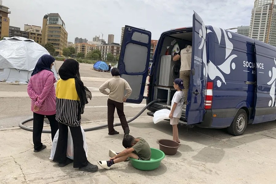 Un grupo de desplazados acude a la lavar su ropa a una tintorería ambulante gestionada por una ONG en Beirut.