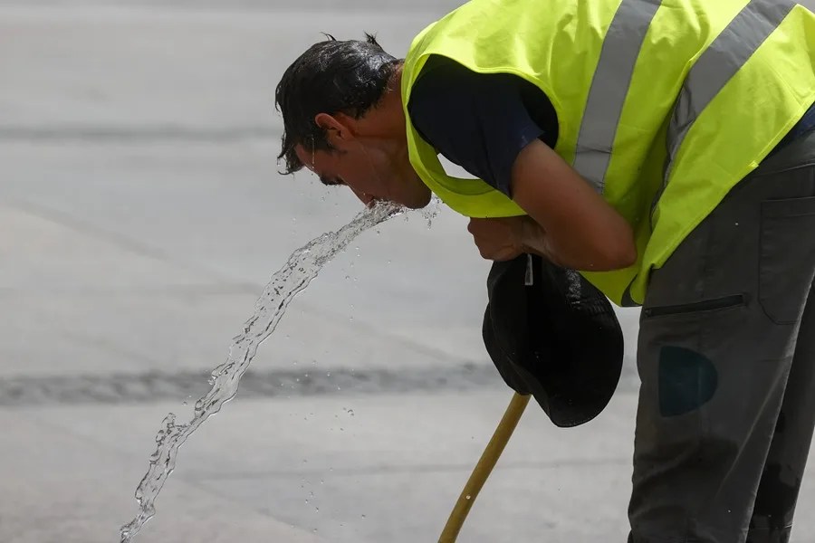 Un trabajador se refresca con una manguera en una calle de Madrid