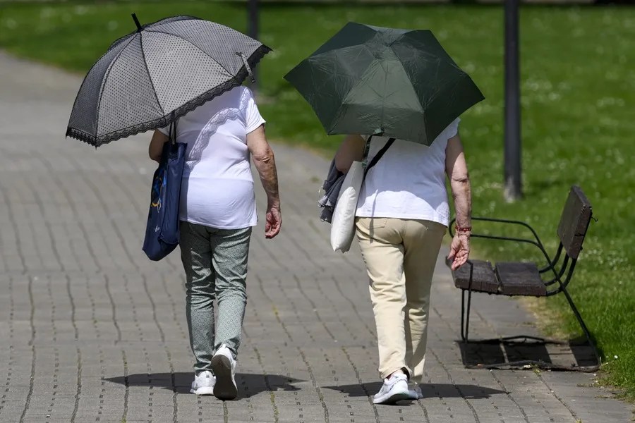 Dos personas se protegen del sol con paraguas en Oviedo.