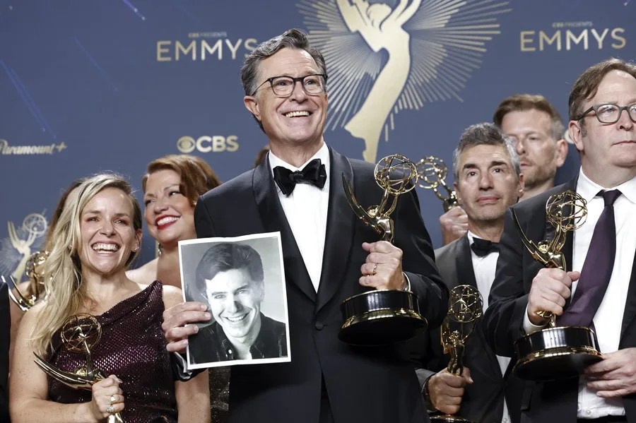 El comediante estadounidense Stephen Colbert (C) sostiene una fotografía mientras posa con el premio al Mejor Programa de Entrevistas
