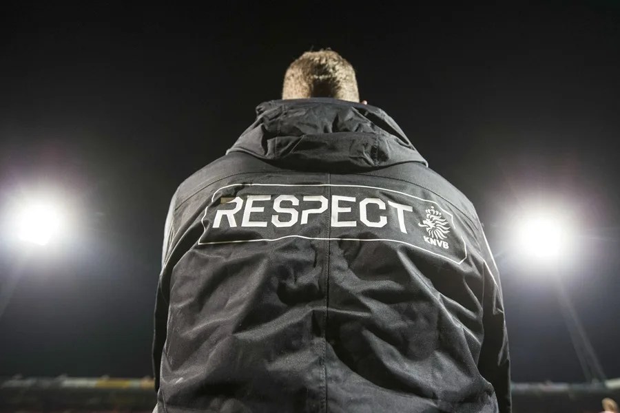 cuarto árbitro lleva una chaqueta con la palabra «respeto» durante el partido