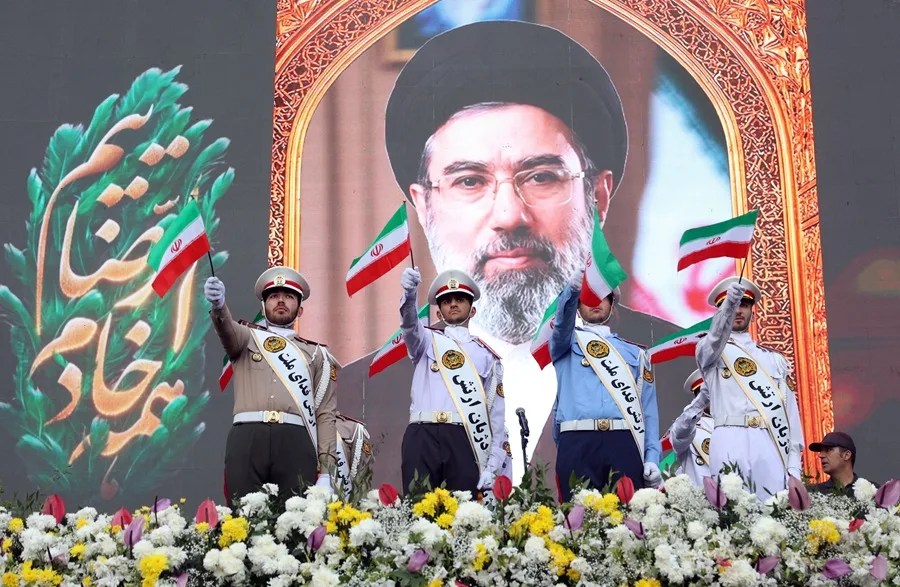 Miembros del ejército iraní ondean banderas nacionales frente a un cartel del líder supremo iraní, el ayatolá Mojtaba Khamenei