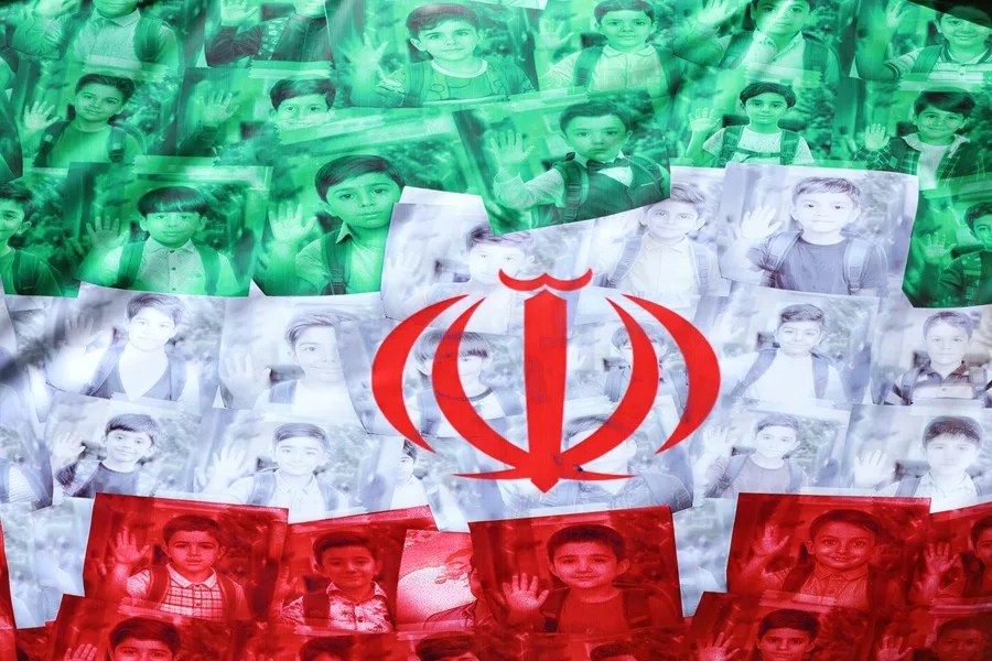 La bandera nacional de Irán, con los retratos de escolares fallecidos en un ataque aéreo estadounidense, ondea en una calle de Teherán