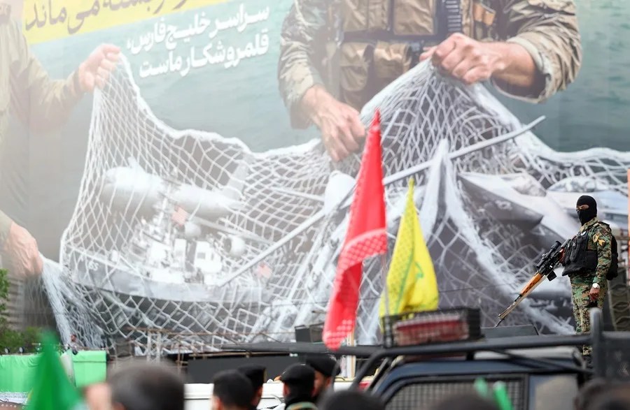 Un soldado vigila mientras los iraníes participan en una manifestación para mostrar su apoyo y solidaridad con el nuevo líder supremo iraní