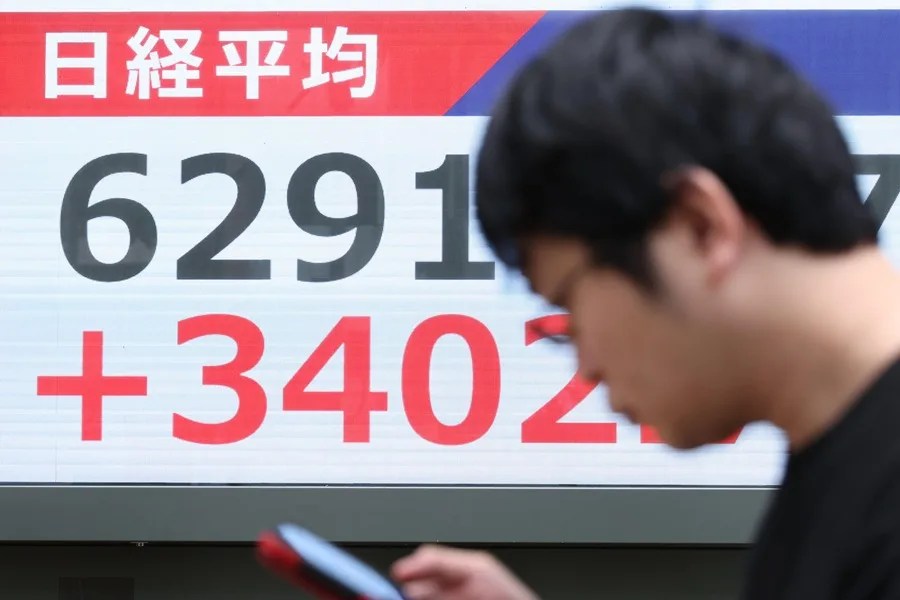 Un hombre pasa junto a una pantalla electrónica que muestra el índice Nikkei en Tokio
