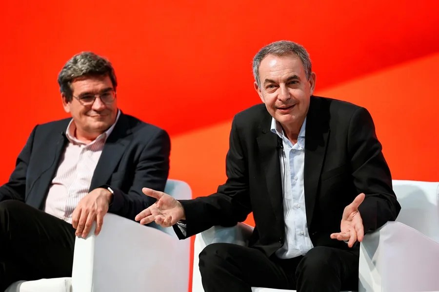 El ex presidente Jose Luis Rodriguez Zapatero (d) y el ministro de Inclusión, Seguridad Social y Migraciones, Jose Luis Escrivá (i)