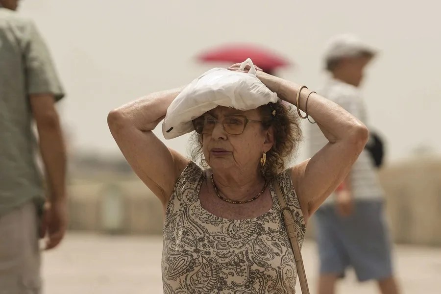 Un turista se protege del sol mientras cruza el Puente Romano de Córdoba