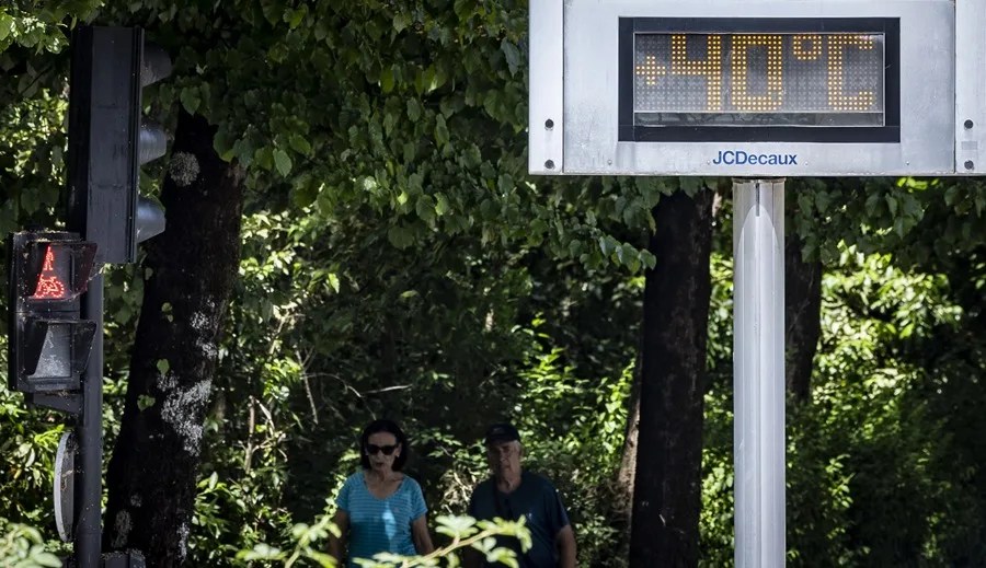 Una pareja pasa junto a un termómetro este lunes San Sebastián