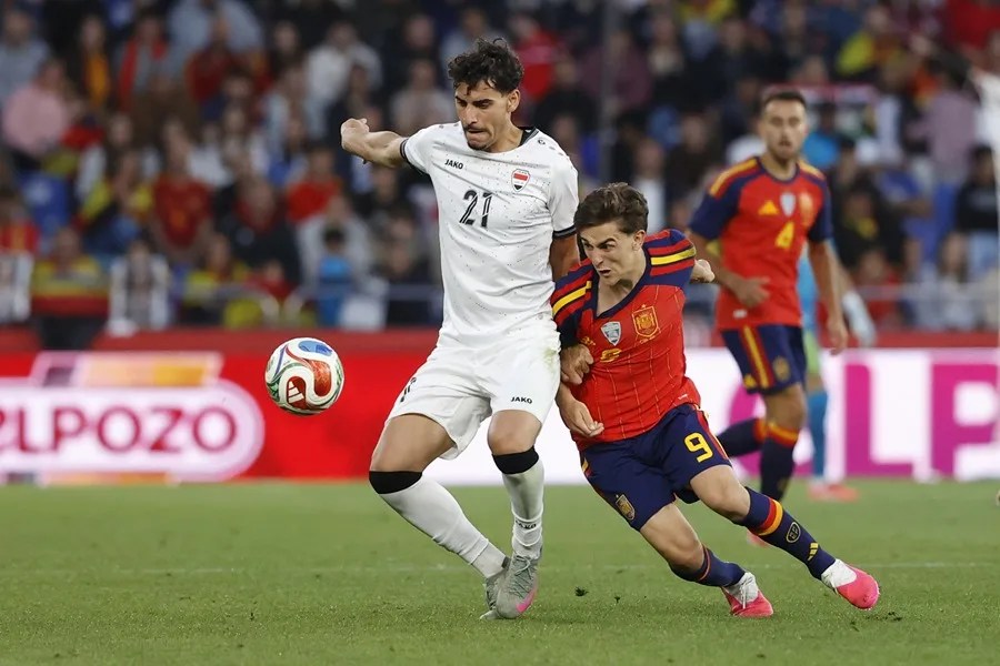 El centrocampista español Gavi disputa un balón ante Marko Farji (i) de la selección iraquí