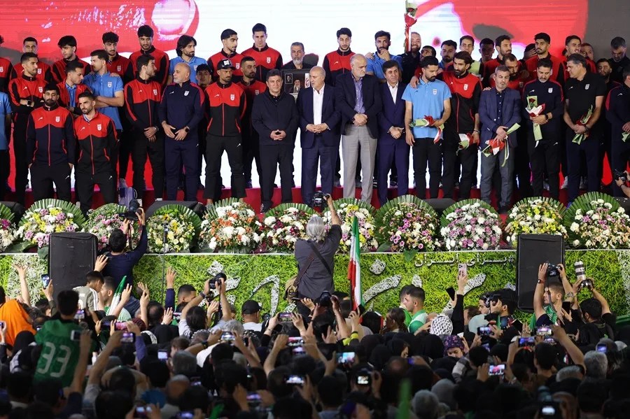 La selección nacional de fútbol de Irán permanece en un podio mientras la gente aplaude durante una ceremonia de despedida en Teherán.