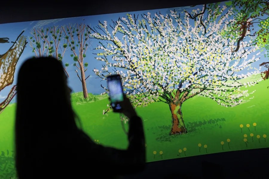 Un visitante toma fotografías de la pintura compuesta realizada con iPad titulada 'Un año en Normandía' del artista británico David Hockney