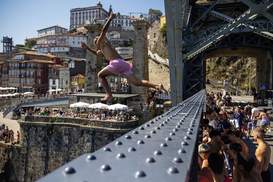 Unos lugareños saltan desde el puente Don Luis al río Duero para refrescarse durante una jornada calurosa en Oporto