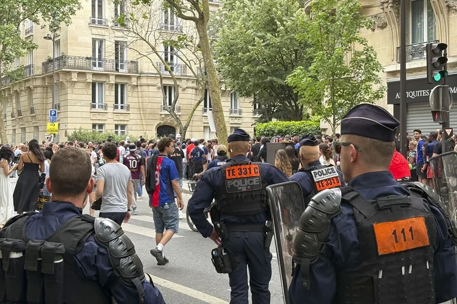 Agentes antidisturbios junto a las decenas de miles de aficionados que se congregaron este domingo en Campo de Marte de París,