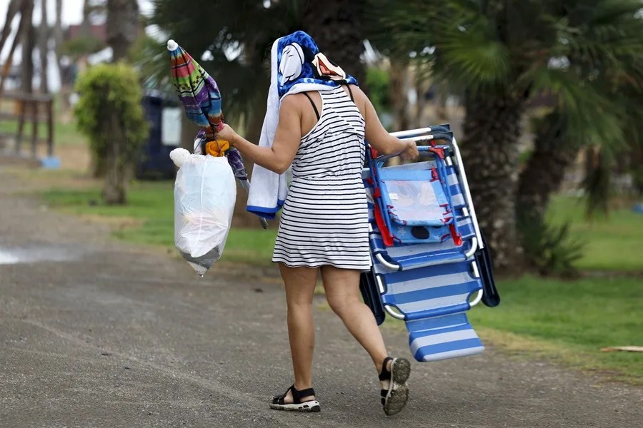 Una mujer se retira de la playa debido a la lluvia, que ha sorprendido a los bañistas en la playa del Rincón de la Victoria