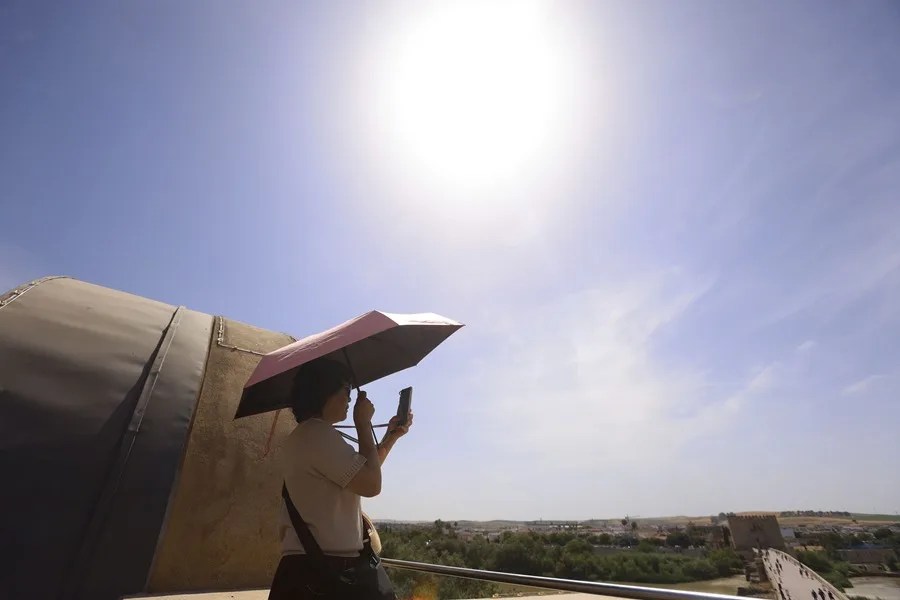 Turistas se protegen del sol con paraguas en Córdoba.