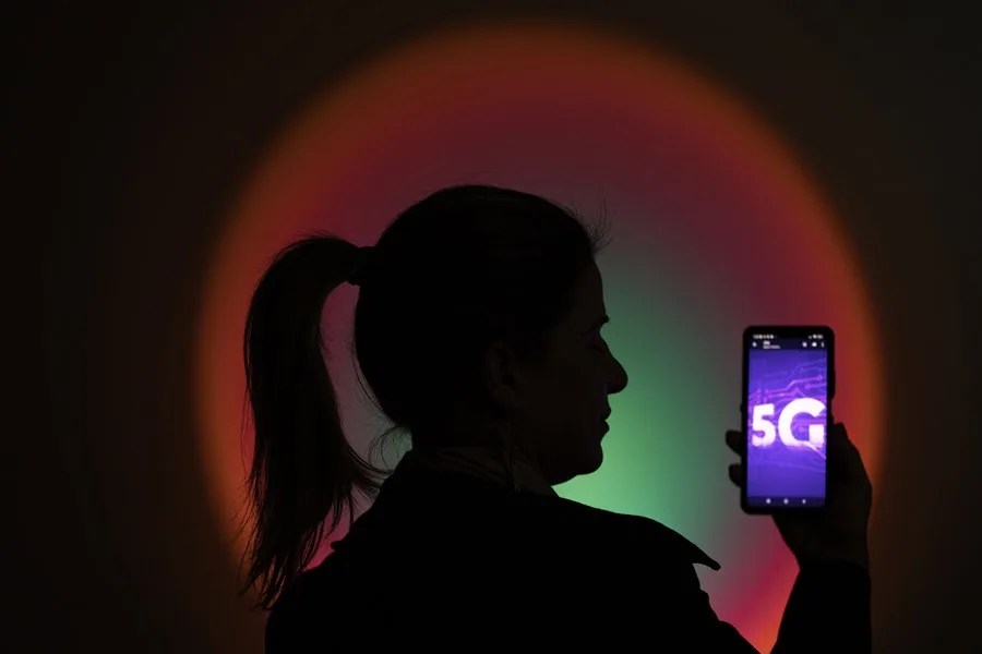 Una mujer sostiene un celular con una imagen de la nueva tecnología 5G