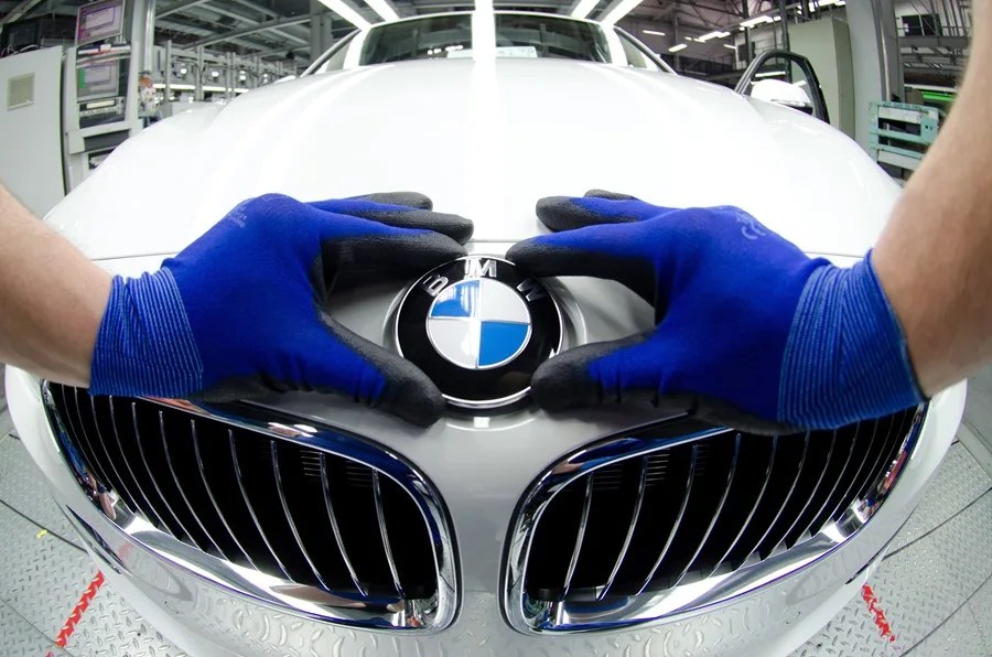 Un empleado coloca el logotipo de BMW en el capó de un coche nuevo