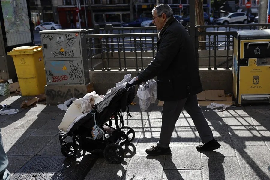 Un hombre pasea con su nieto por una calle de Madrid.