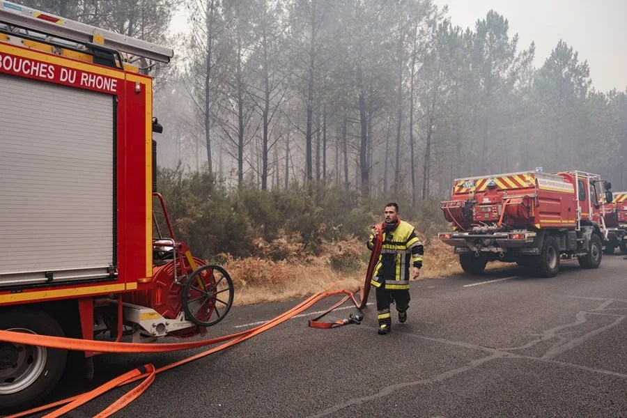 Un bombero lleva una manguera en una línea de apoyo entre Lacanau y Sainte-Hélène en la región de Burdeos, en el suroeste de Francia.