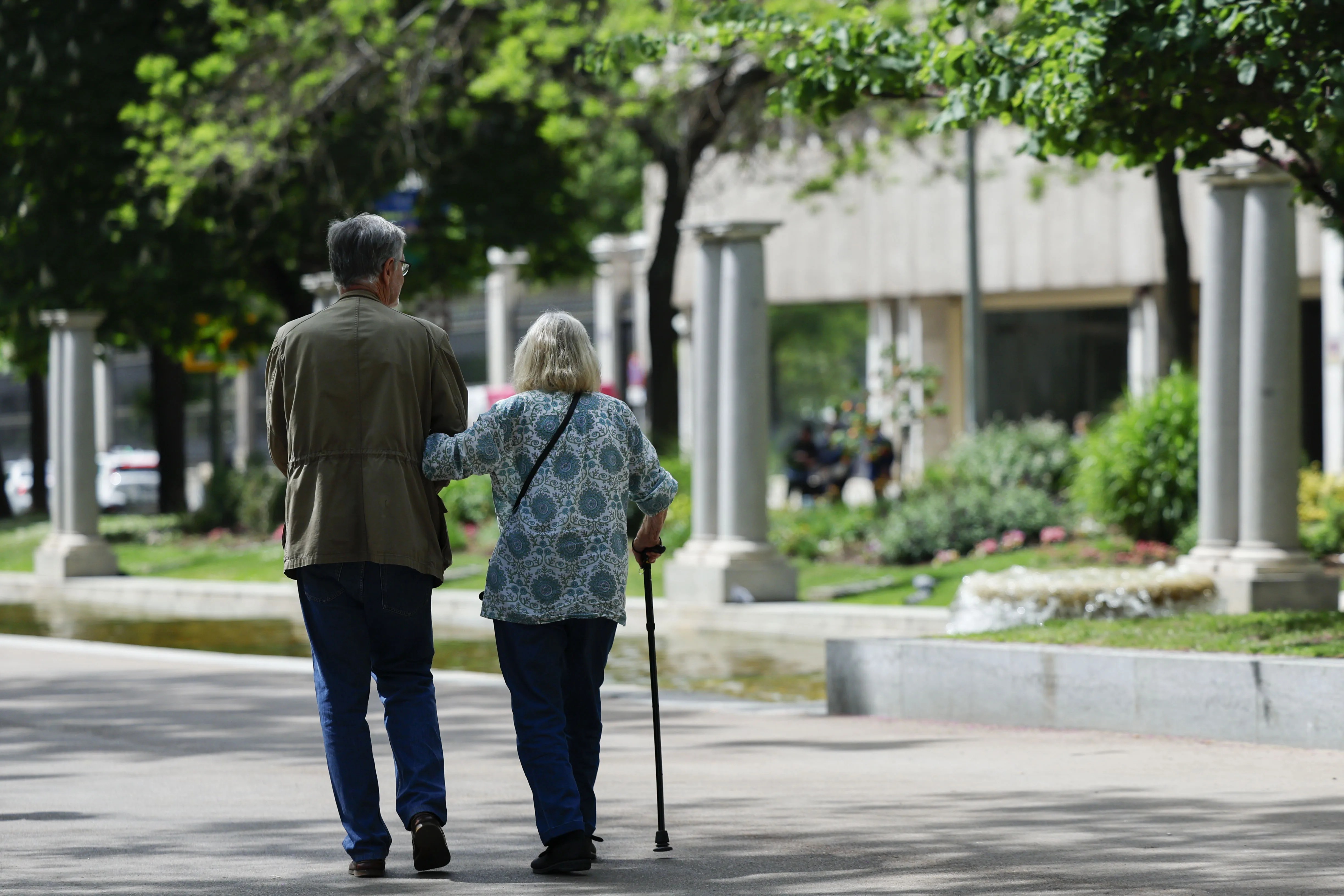 Una mujer camina ayudada por un cuidador en una calle. EFE/Mariscal