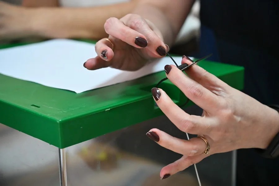 La presidenta de una mesa coloca un precinto en una urna en un colegio electoral.
