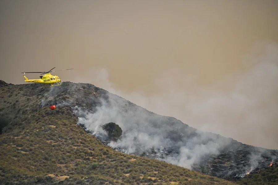 Un helicóptero del servicio de extinción de incendios arroja este viernes agua sobre uno de los focos del incendio forestal declarado en Los Gallardos
