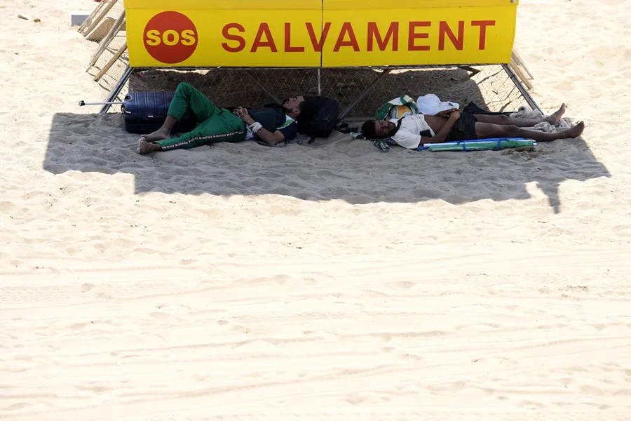 Unos jóvenes se protegen de la calor en una playa de Barcelona