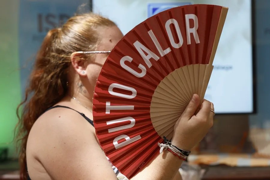 Una mujer se resguarda del sol con un abanico