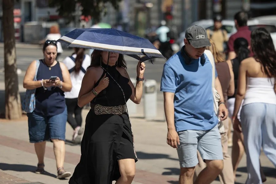 Una mujer se protege del calor con un paraguas