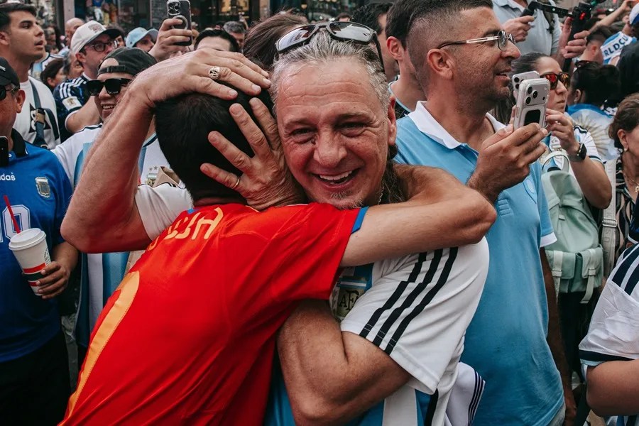 Un aficionado argentino abraza a un aficionado (izq.) de España mientras los aficionados argentinos al fútbol toman Times Square