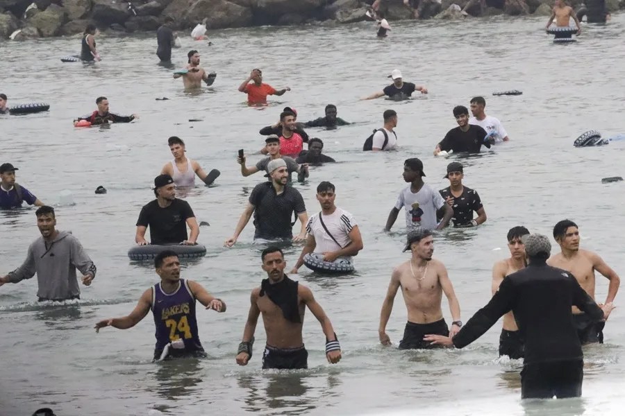 Un grupo de inmigrantes en la playa junto al paso fronterizo del Tarajal en Ceuta este viernes.